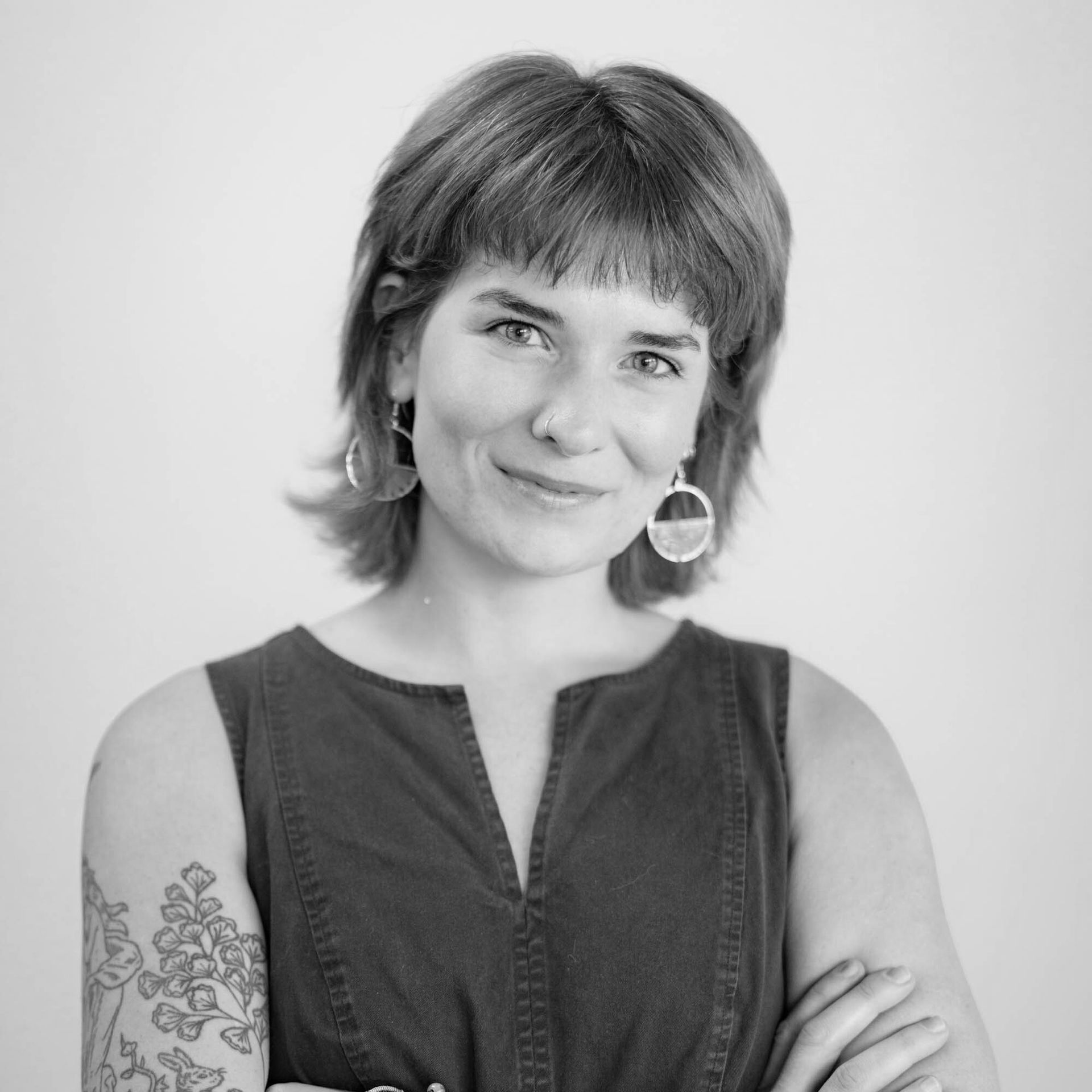 A woman with a tattoo on her arm is smiling in a black and white photo.