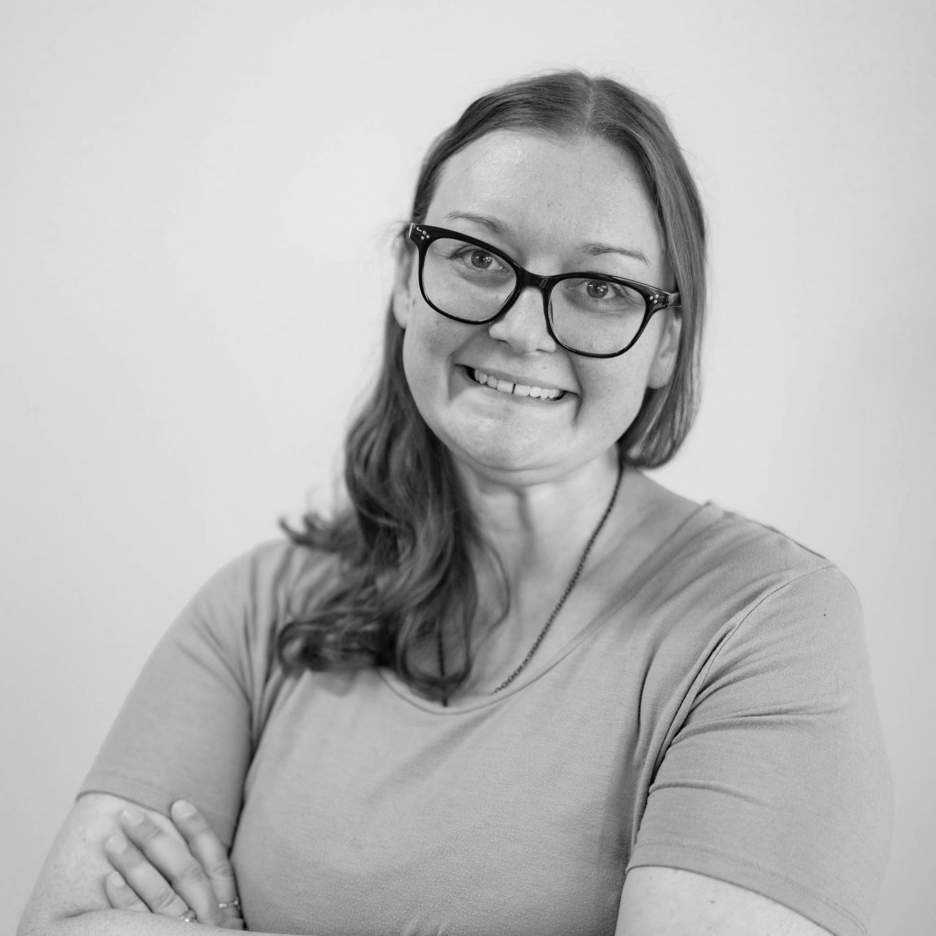 A woman wearing glasses is smiling in a black and white photo.