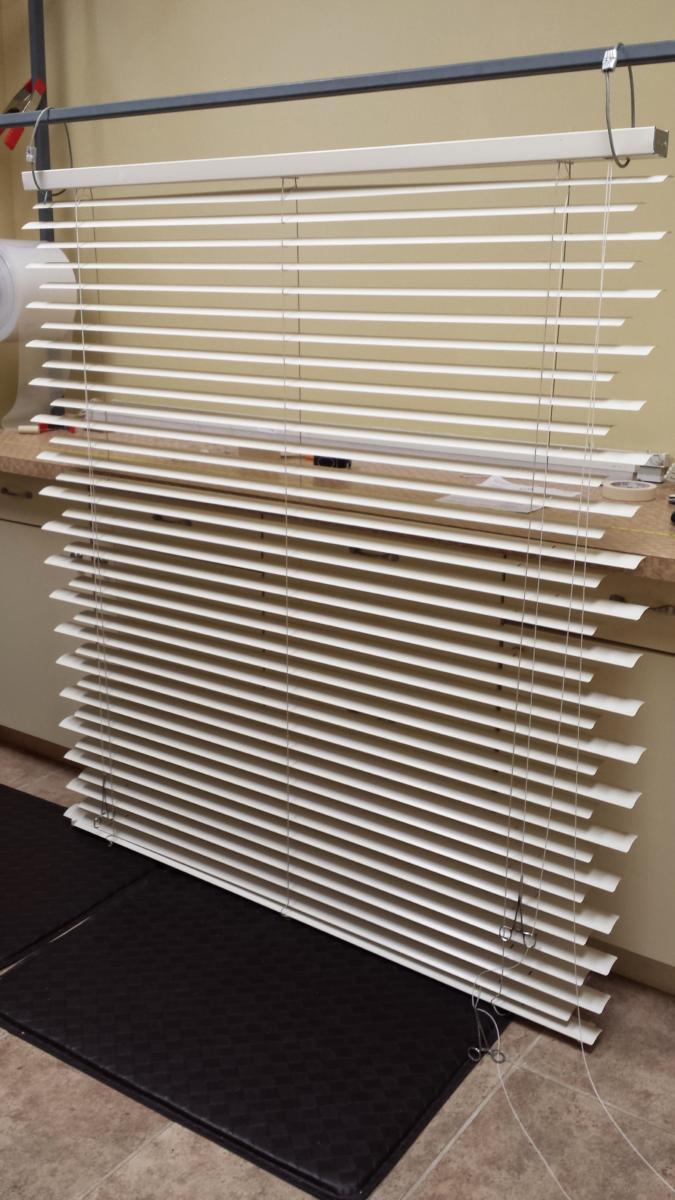 A row of white blinds sitting on a black mat