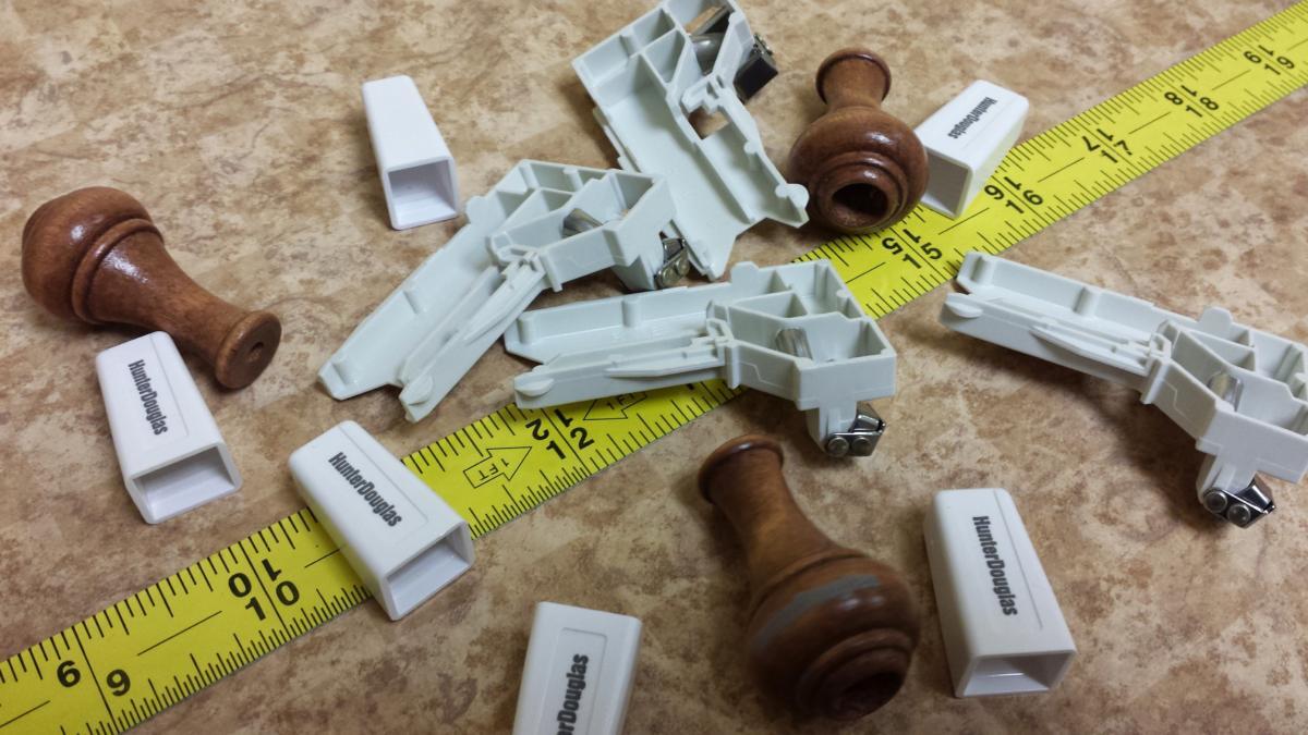 A yellow measuring tape is laying on the floor next to a bunch of pieces of wood and plastic