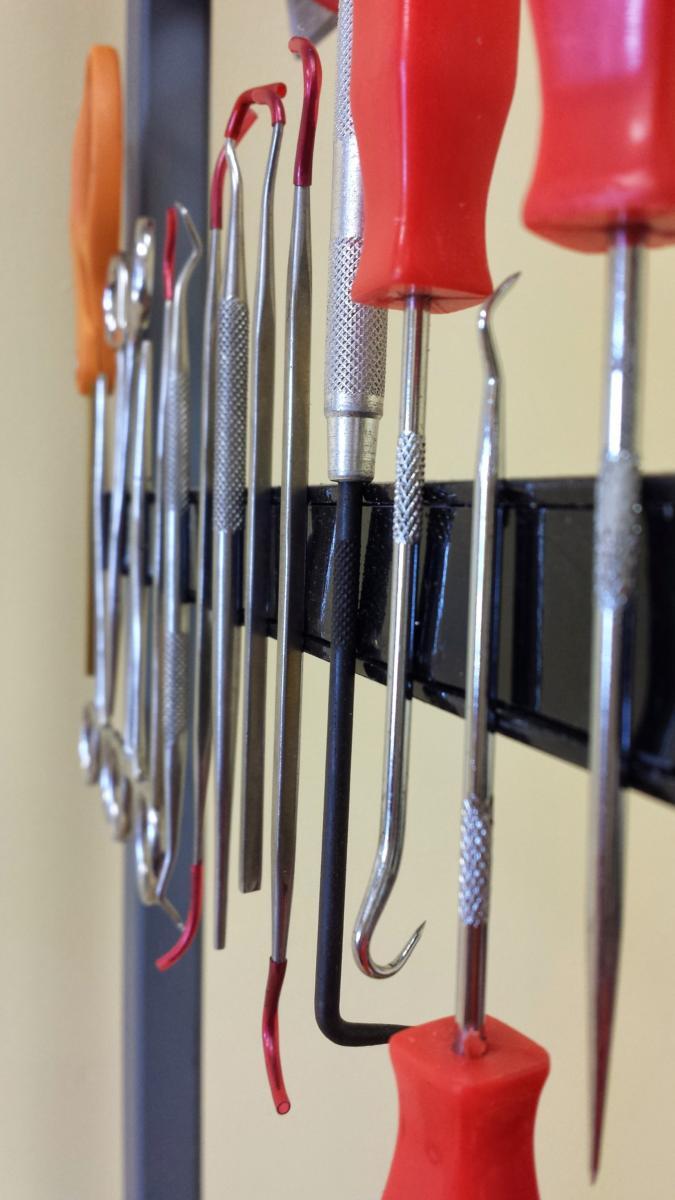 A bunch of tools hanging on a rack including a screwdriver