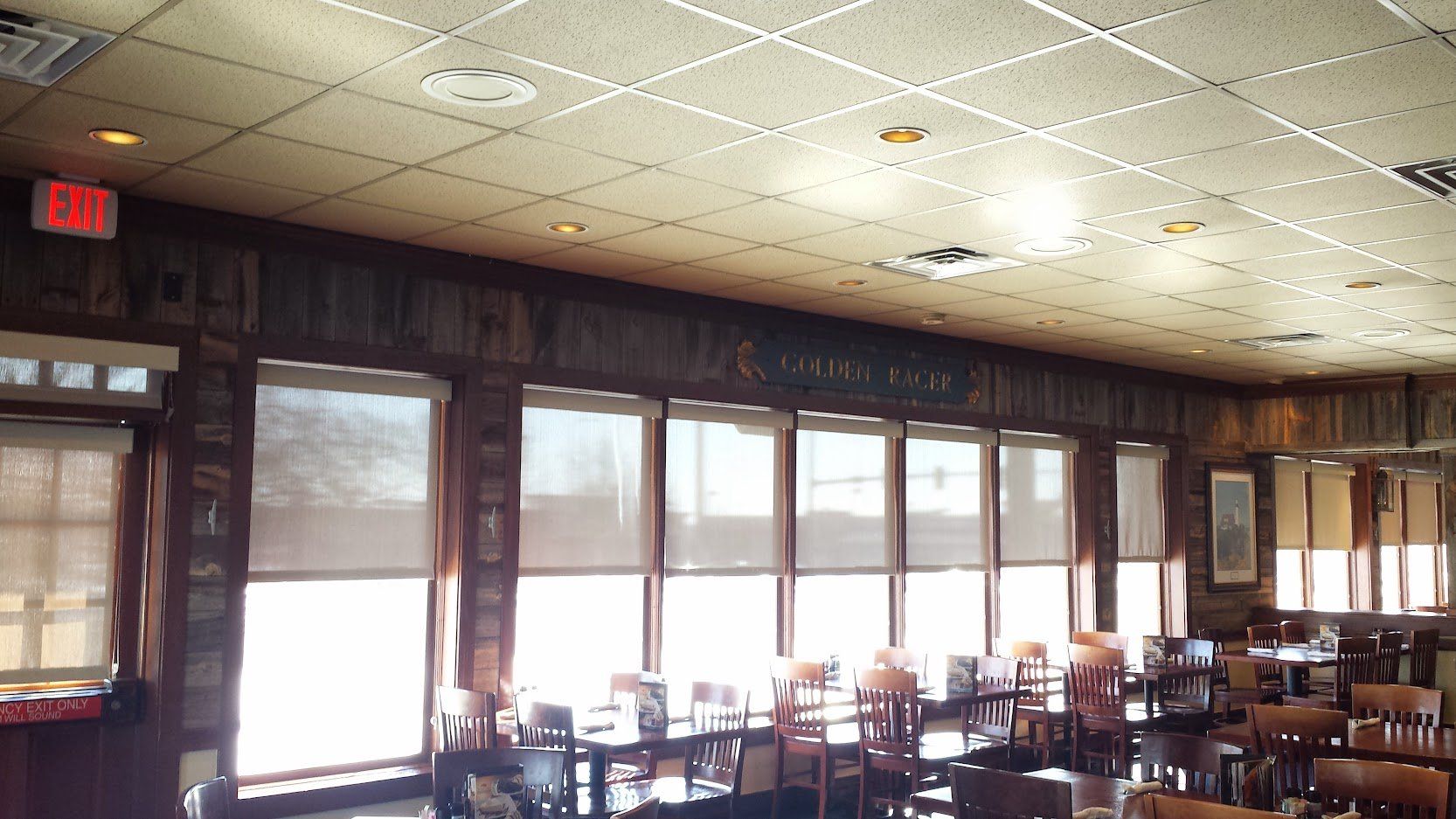 A restaurant with a red exit sign on the ceiling