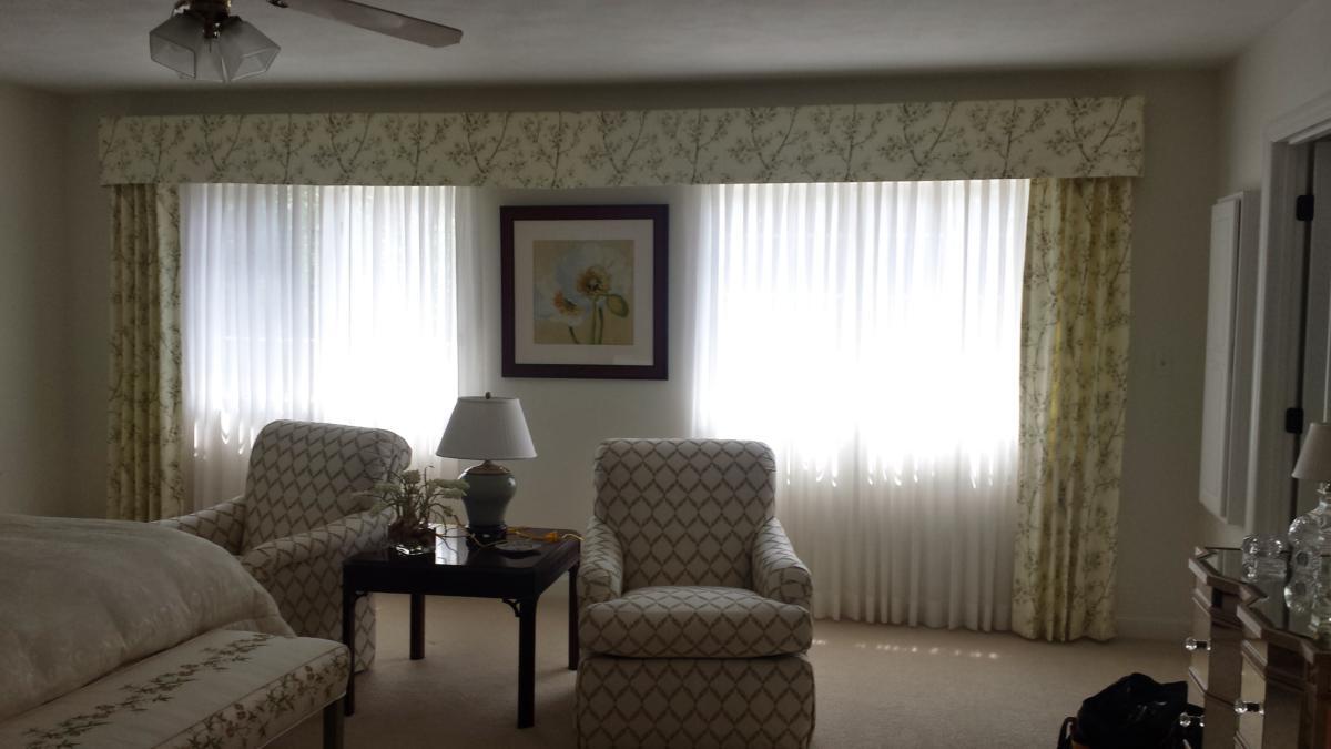 A living room with a couch , two chairs , a table and a ceiling fan.