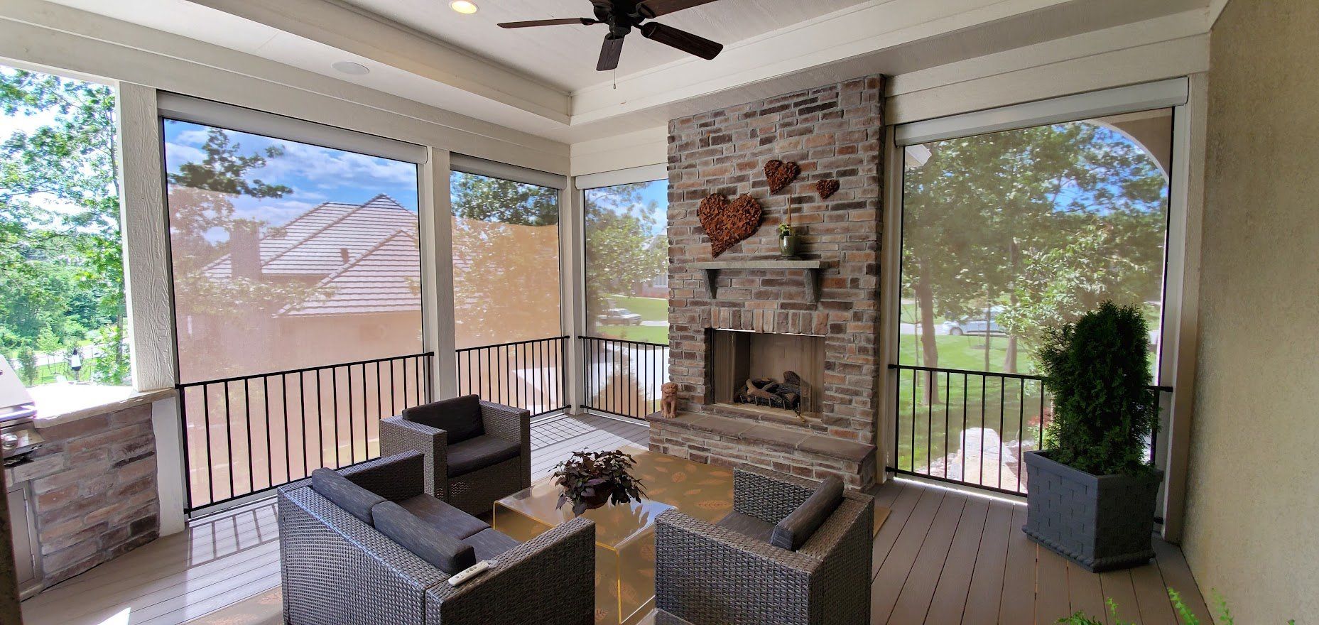 A screened in porch with a fireplace and chairs