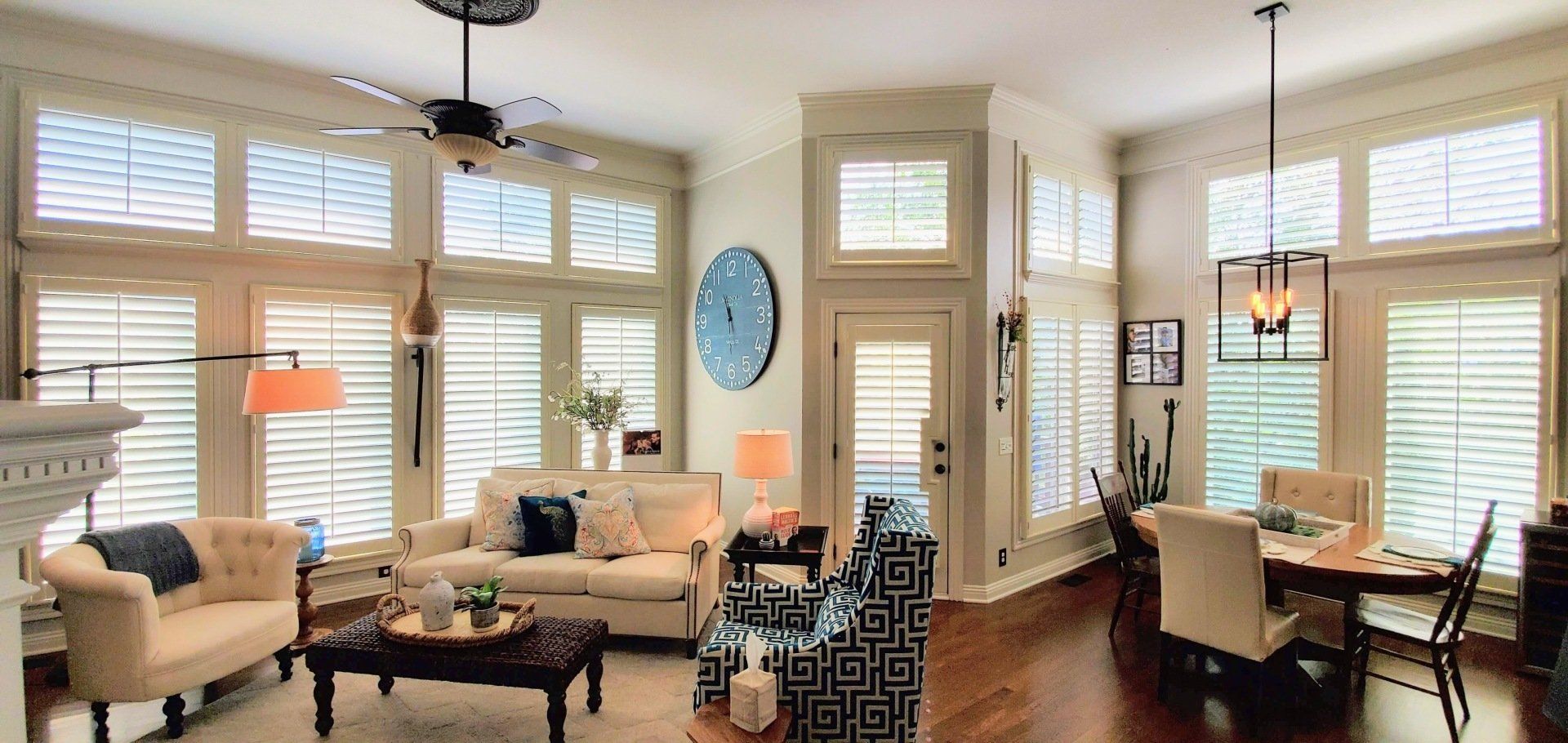 A living room with a couch , chairs , a table and a ceiling fan.