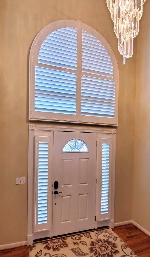 A white door with shutters on it and a large window above it.