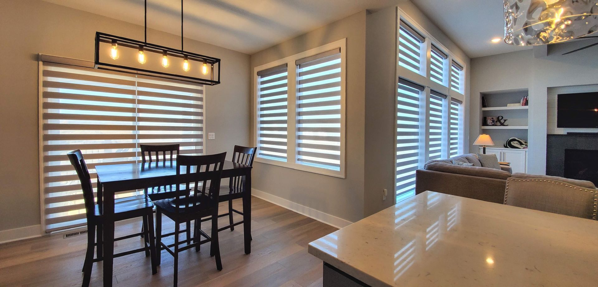A dining room with a table and chairs and shutters on the windows.