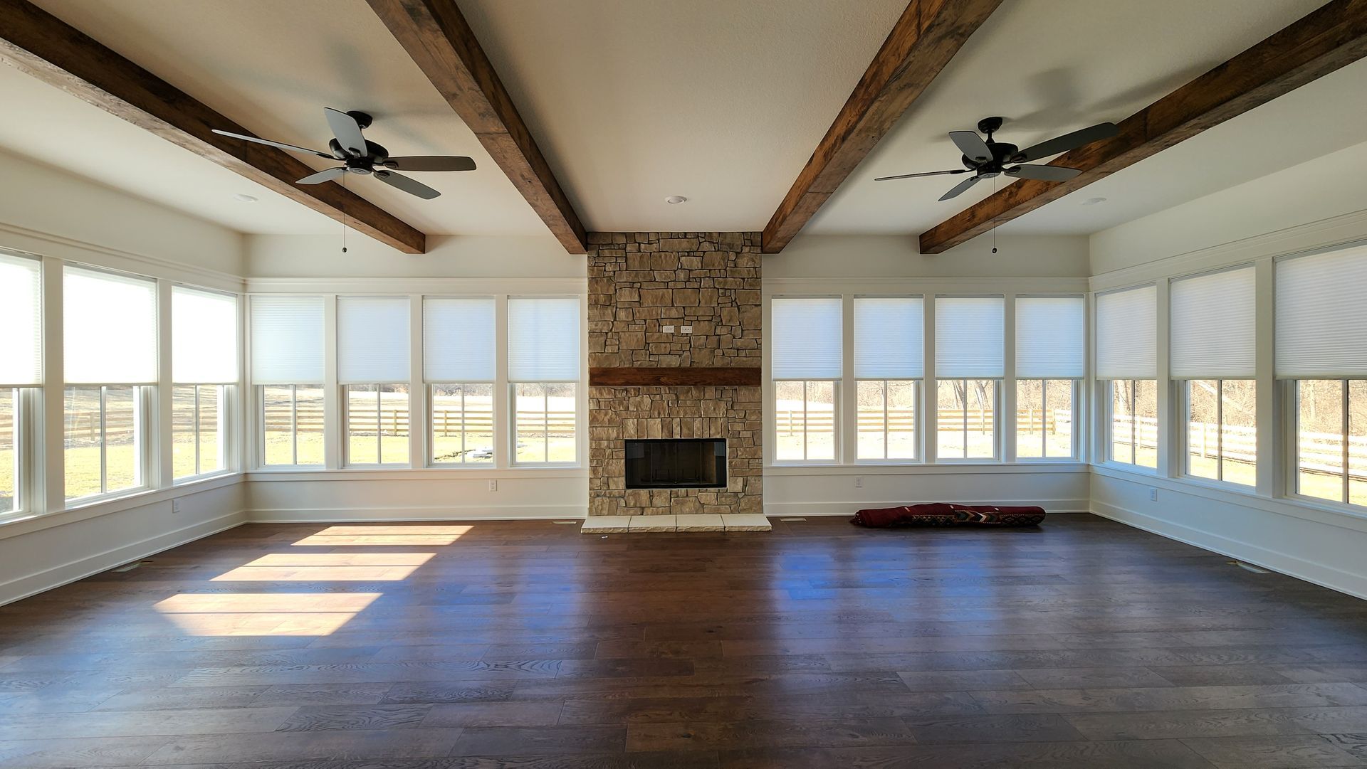 A large empty room with a fireplace and lots of windows.