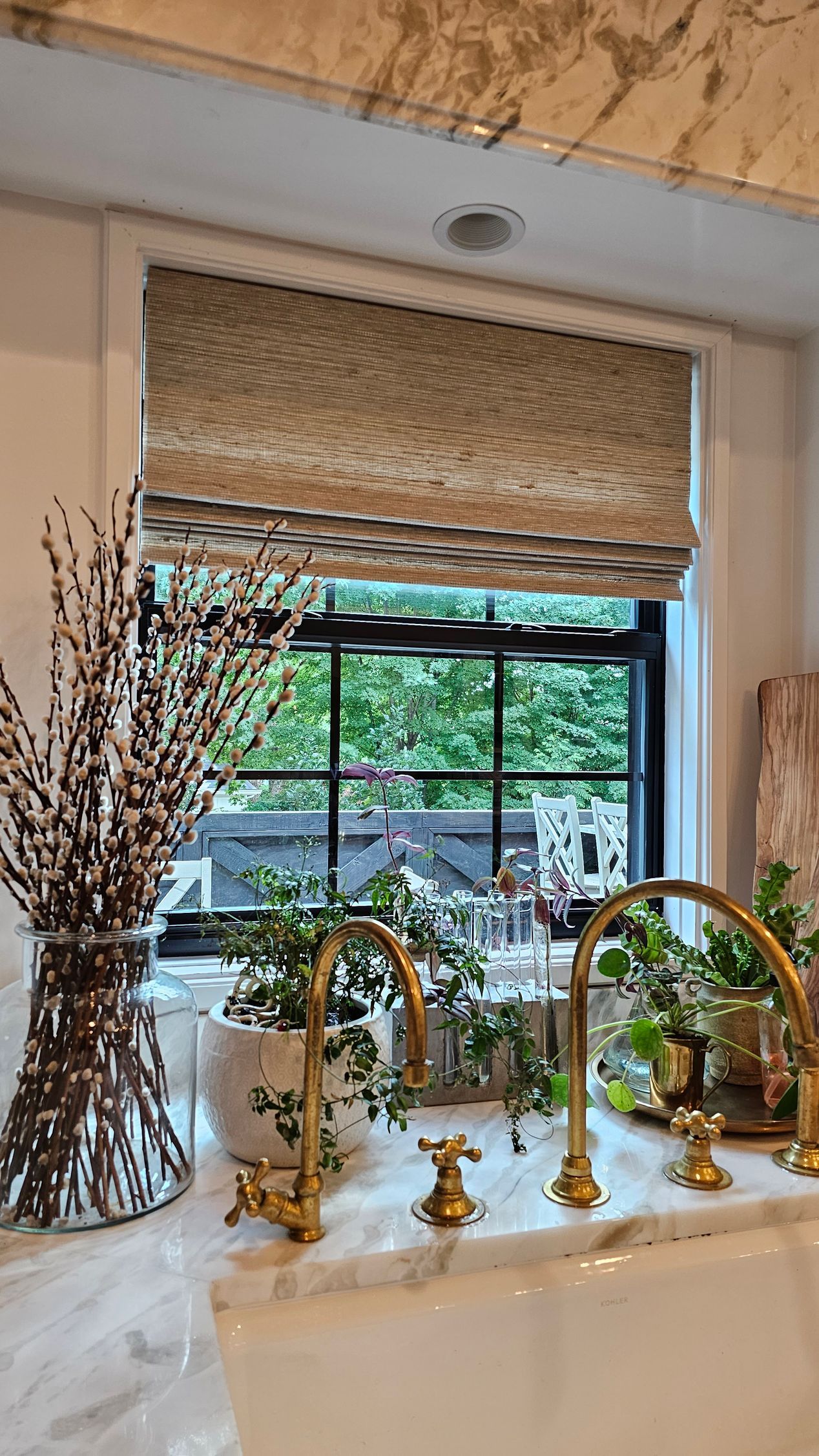 A kitchen sink with a window and a vase of flowers on the counter.