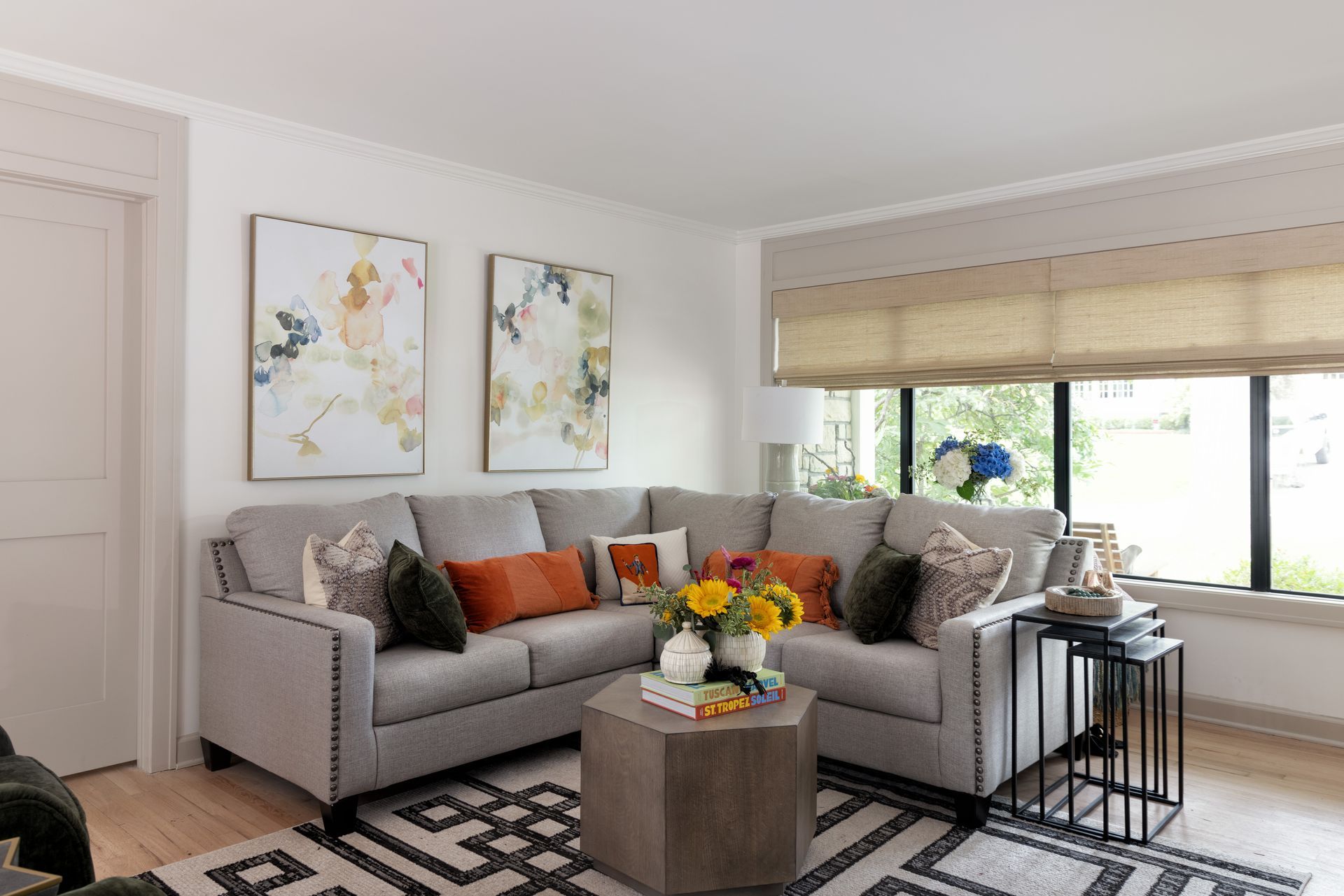 A living room with a couch , coffee table , and two paintings on the wall.