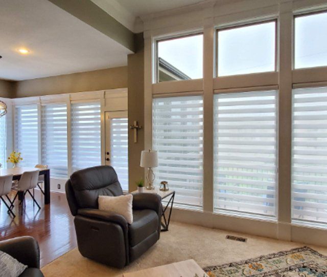 A living room with a black recliner and white blinds