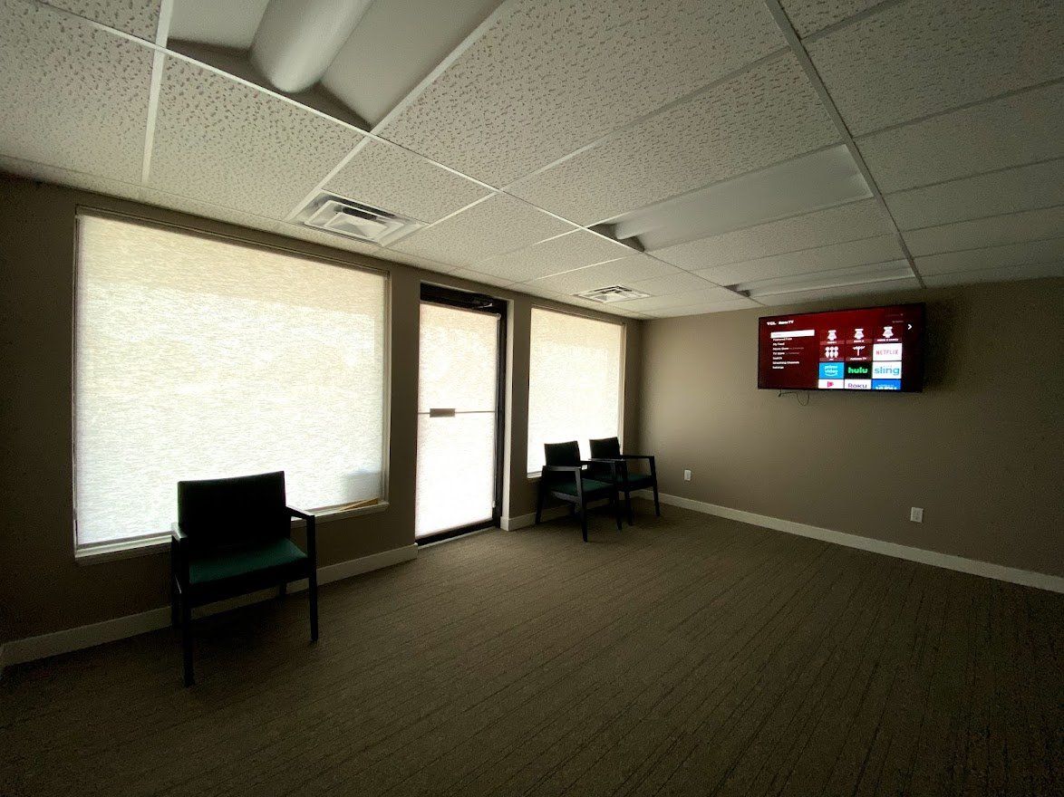 A waiting room with chairs and a tv on the wall