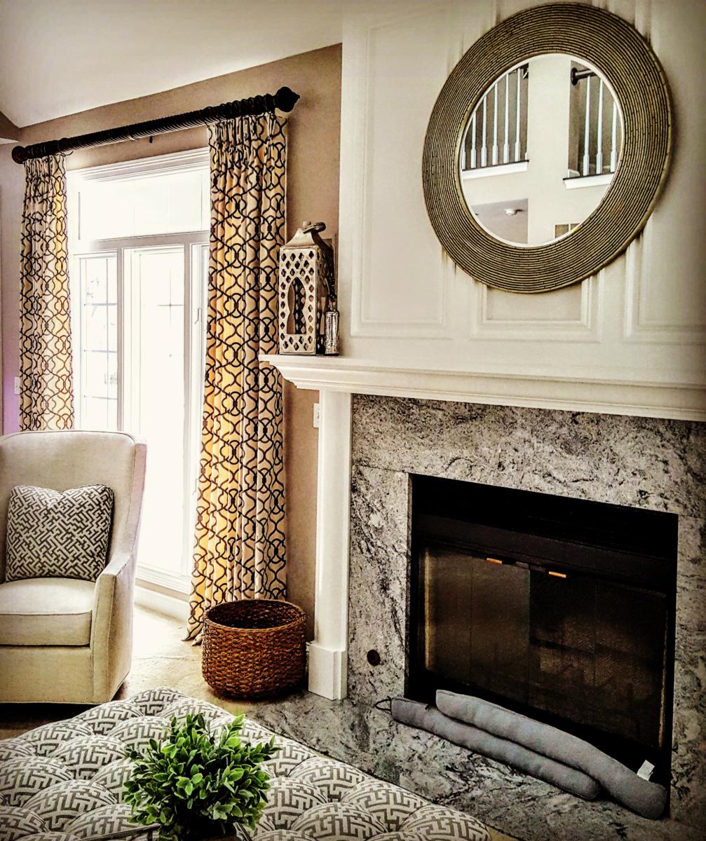 A living room with a fireplace , chair , coffee table and mirror.