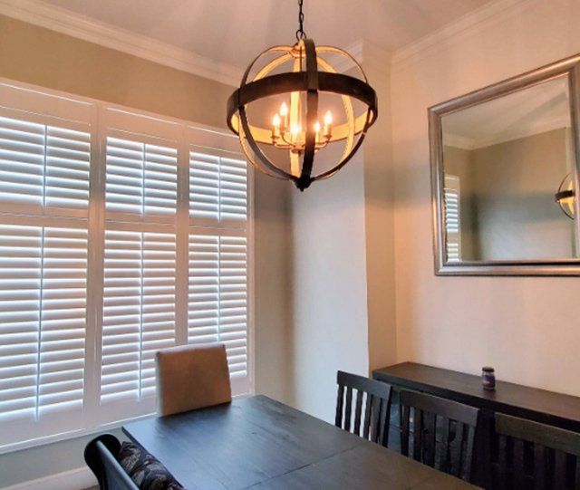 A dining room with a table and chairs and a chandelier hanging from the ceiling