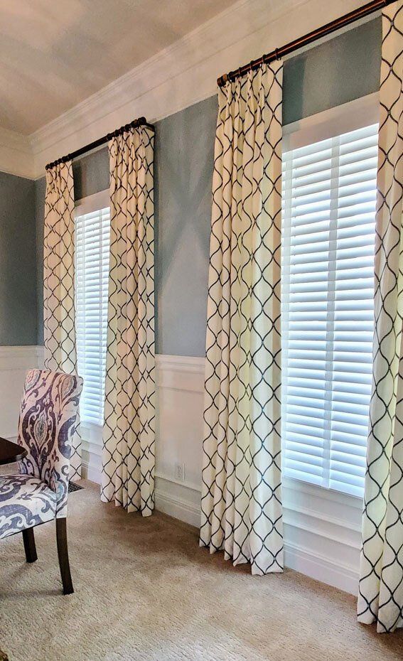 A living room with a chair , curtains and shutters.