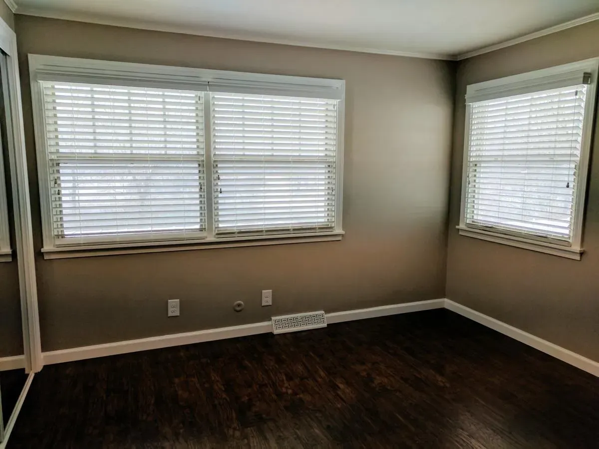 An empty room with two windows and a mirror.