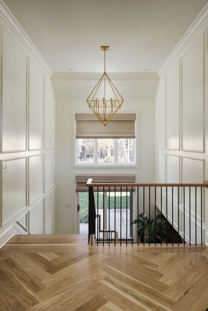 A staircase with a wooden railing and a chandelier hanging from the ceiling.