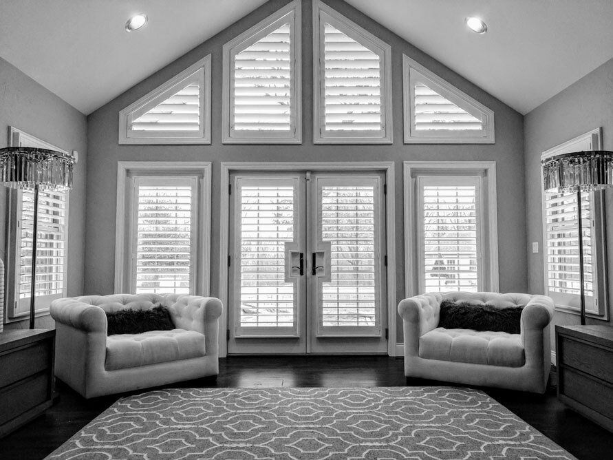 A black and white photo of a living room with two chairs and a rug.