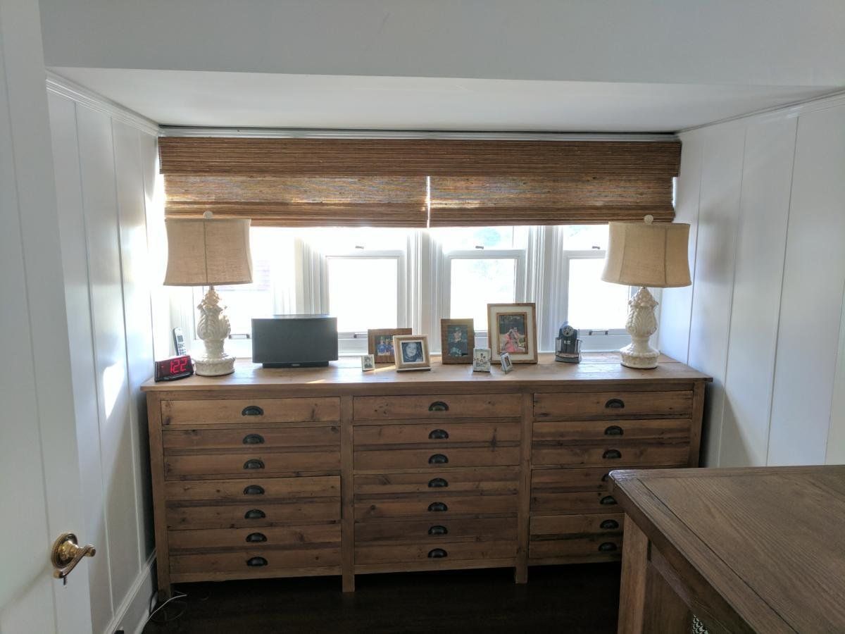 A room with a dresser and lamps and a window