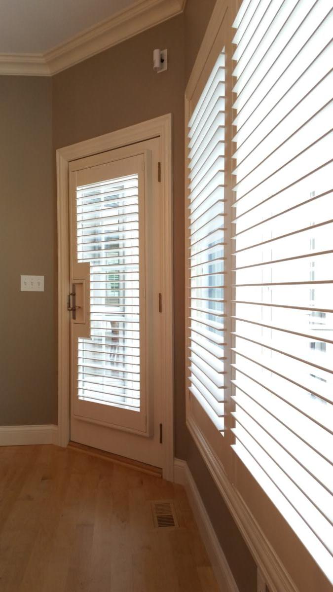 An empty room with blinds on the windows and a door