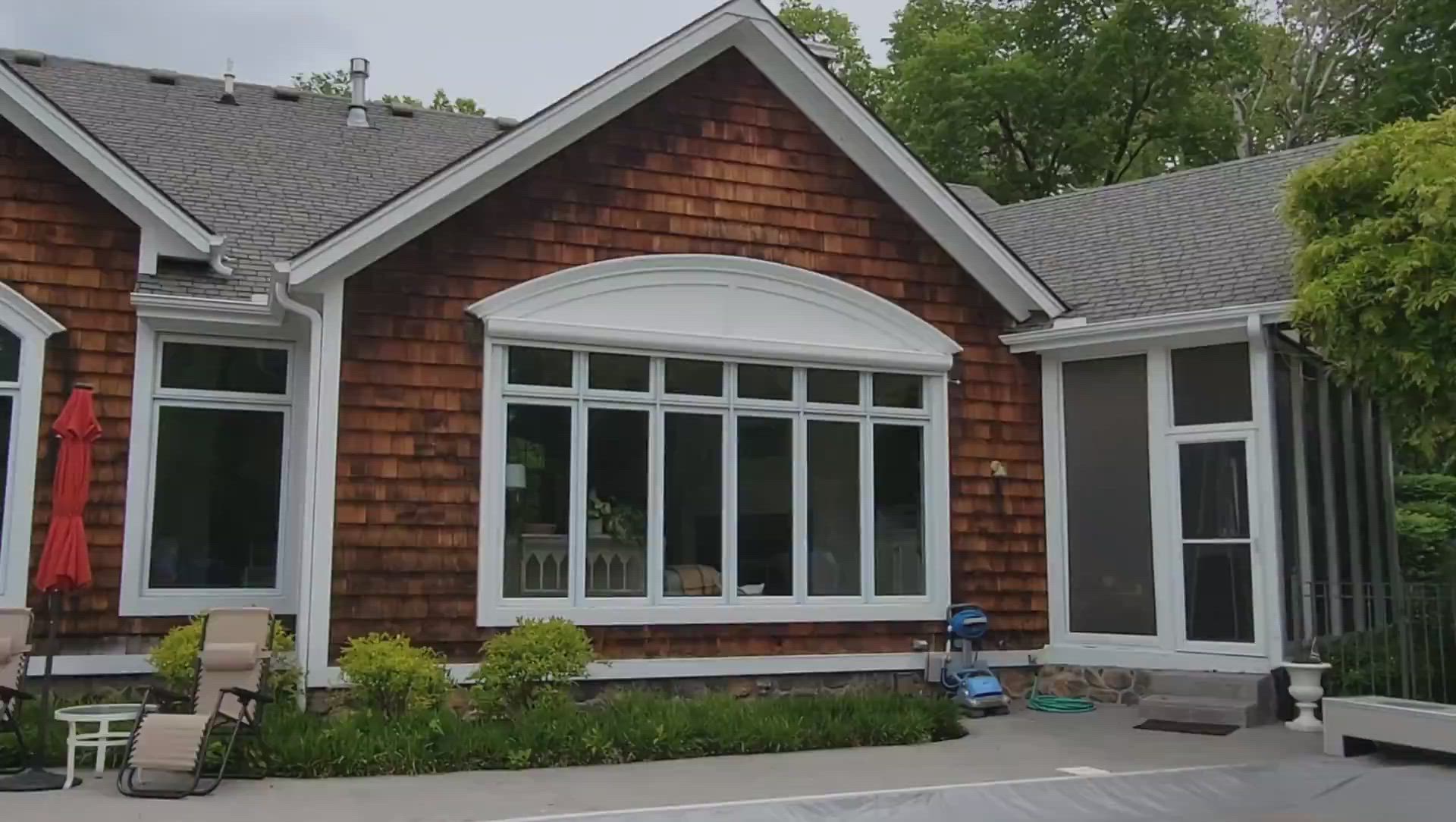 A brick house with white windows and a screened in porch