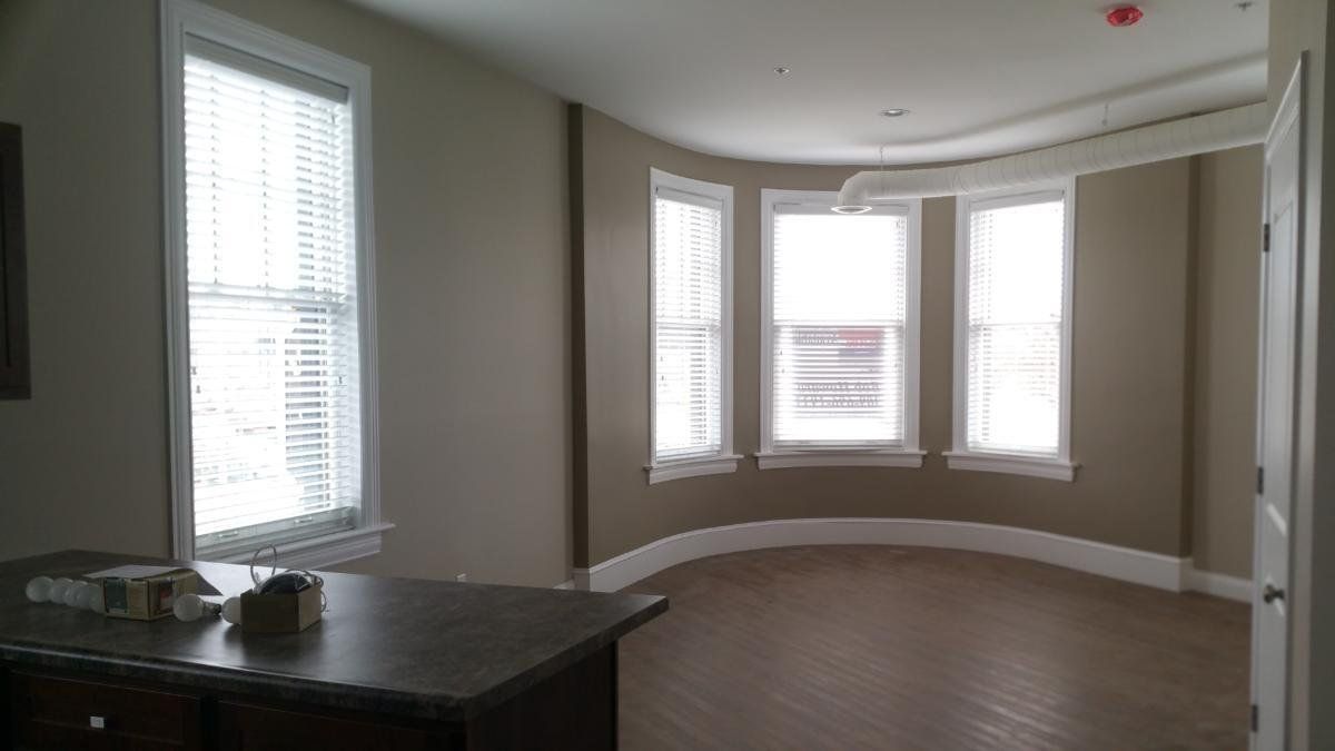 An empty room with a large bay window and a desk.