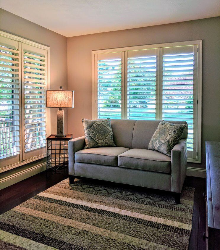 A living room with a couch and shutters on the windows