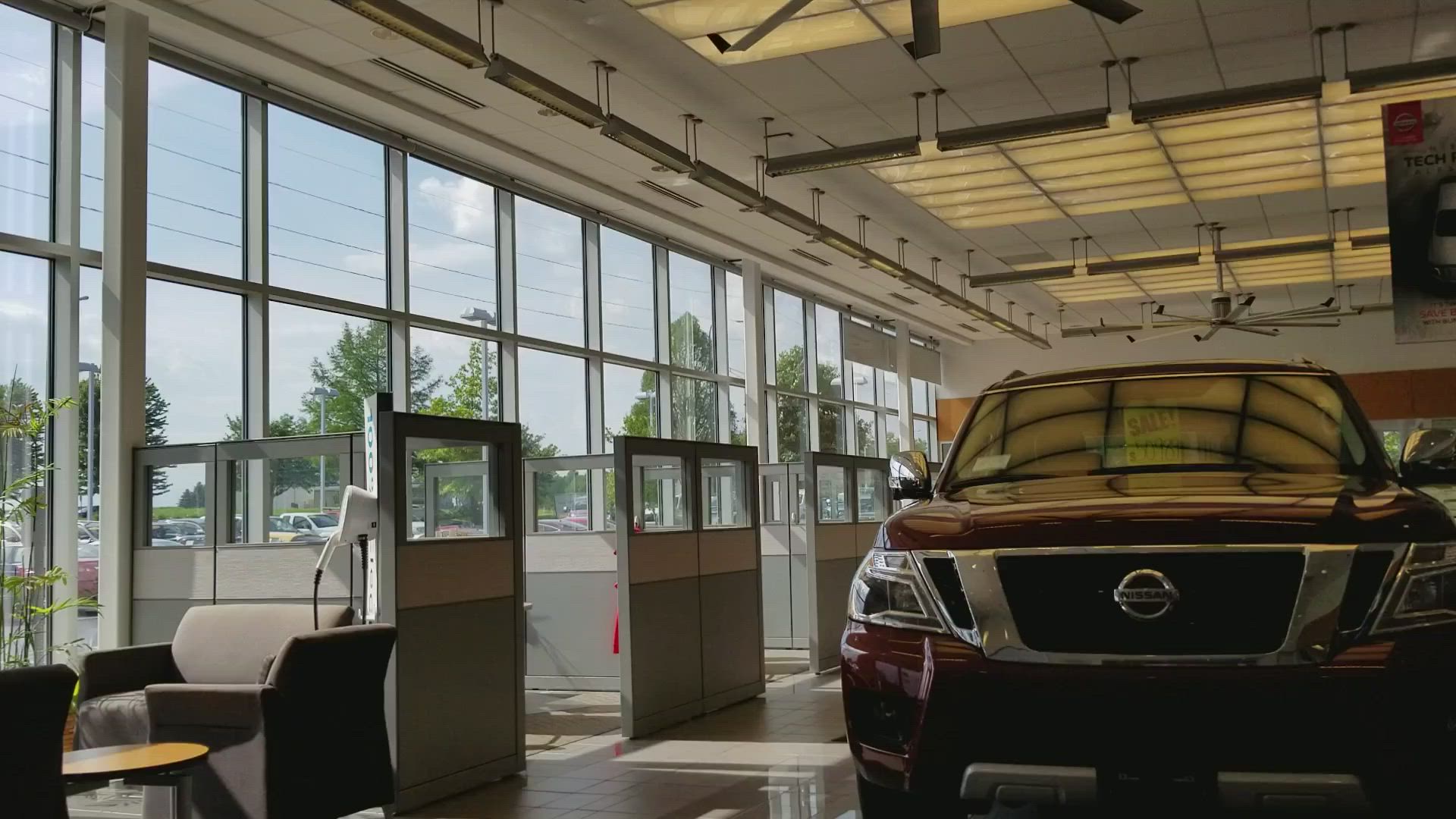 A red nissan car is parked in a car dealership