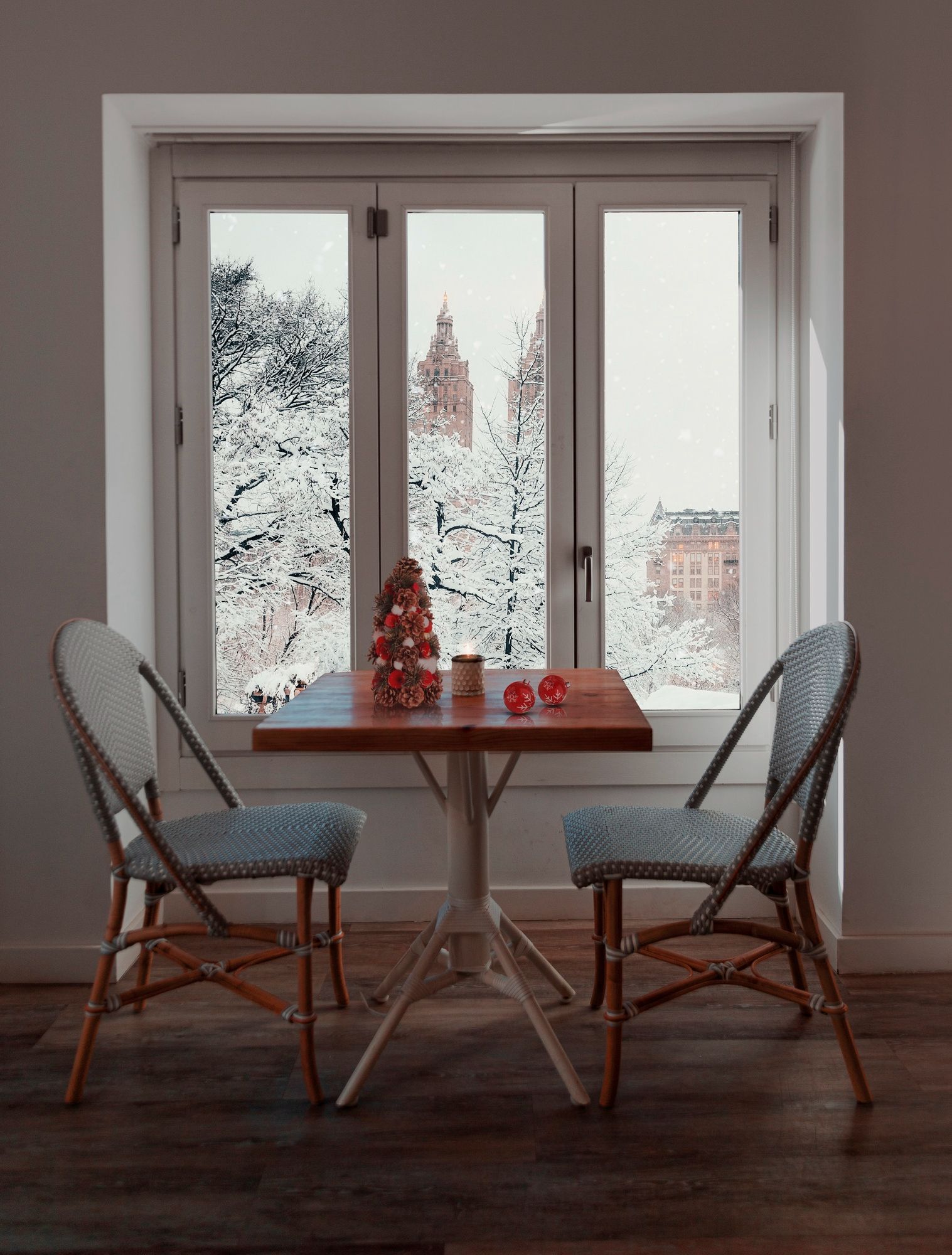 A table and chairs in front of a window with a christmas tree on it.