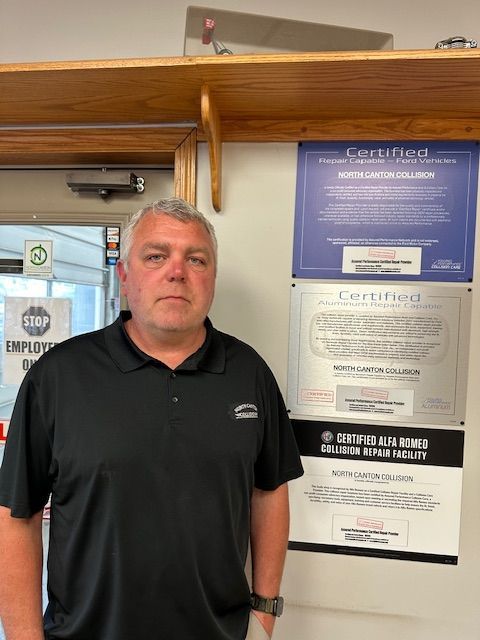 A man in a black shirt is standing in front of a sign that says certified