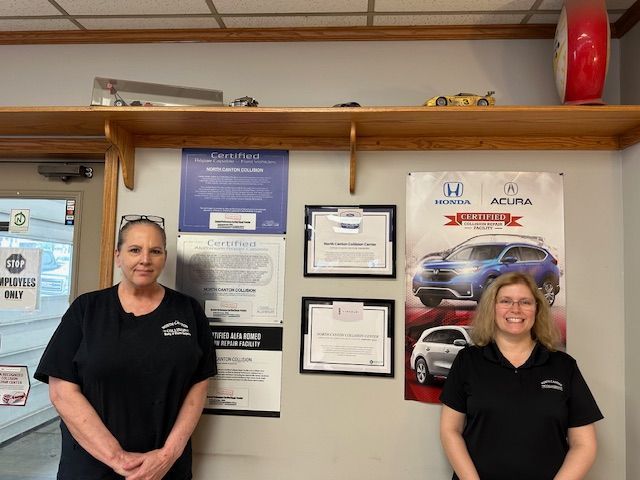 Two women are standing next to each other in front of a honda ad.