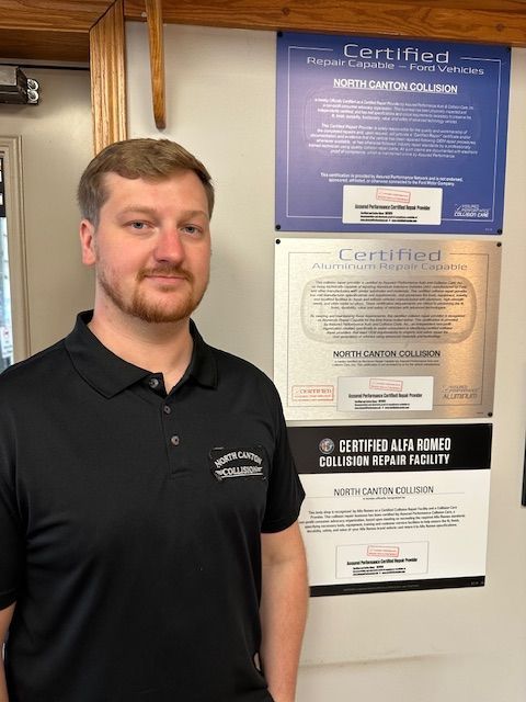 A man is standing in front of a wall with certified signs on it