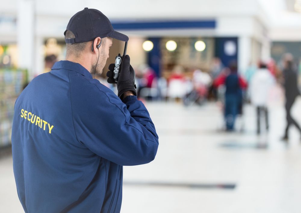 A Security Guard is Talking on a Walkie Talkie in Front of a Crowd of People — Asset Security Group In King Creek, NSW