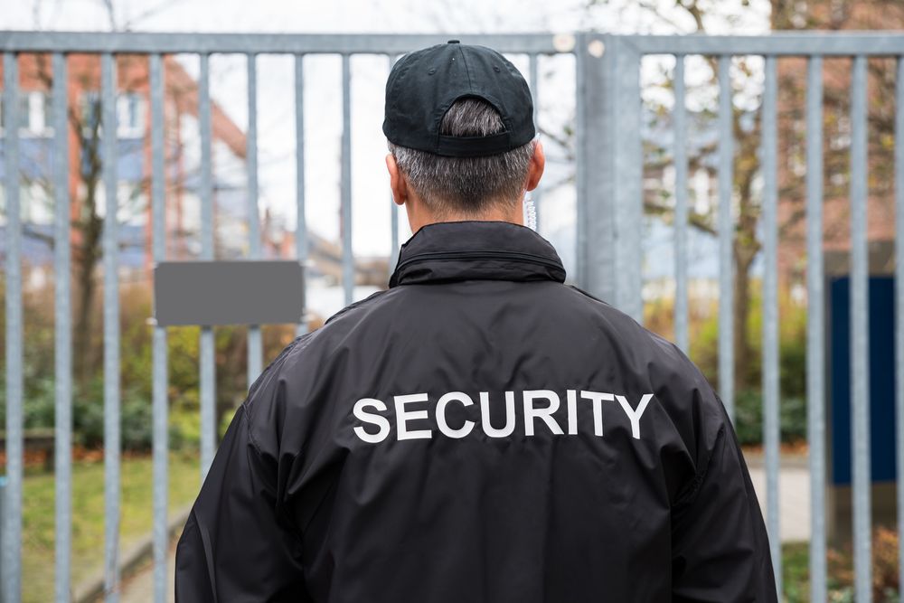A Security Guard is Standing in Front of a Gate — Asset Security Group In King Creek, NSW