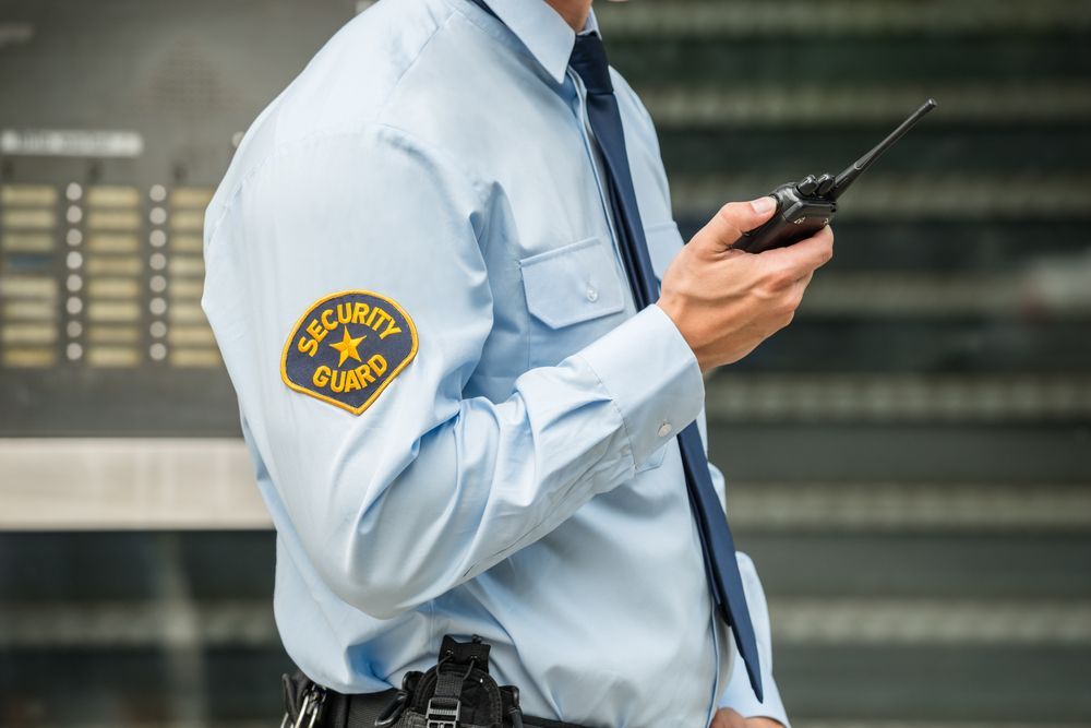 A Security Guard Is Holding A Walkie Talkie In His Hand — Asset Security Group In King Creek, NSW