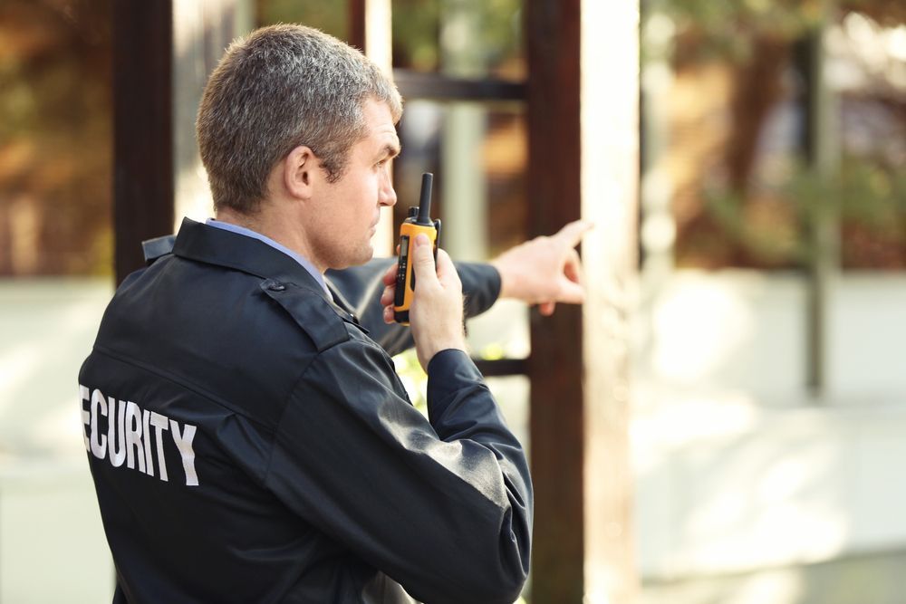 A Security Guard Is Talking On A Walkie Talkie And Pointing — Asset Security Group In King Creek, NSW