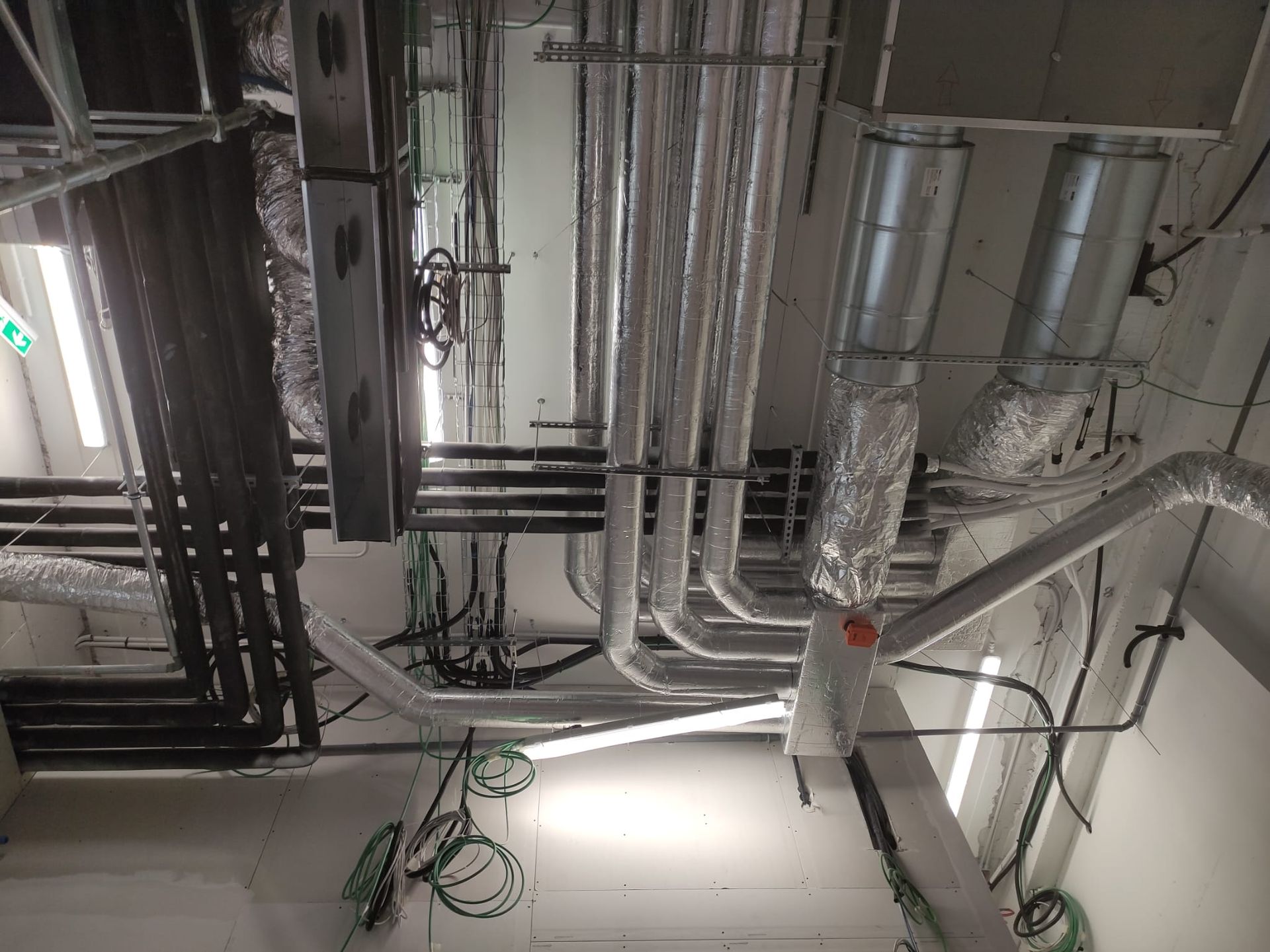 Una stanza con un sacco di tubi e fili che pendono dal soffitto.