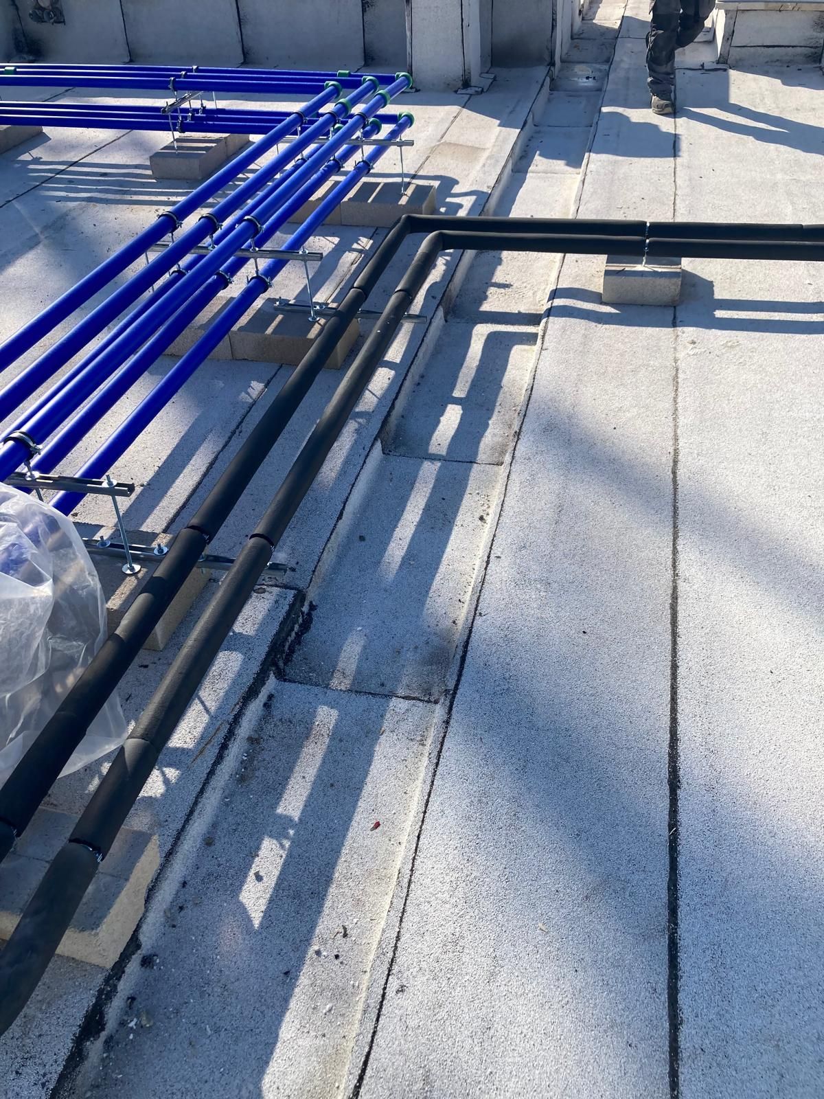 Una fila di tubi blu è appoggiata su un pavimento di cemento.