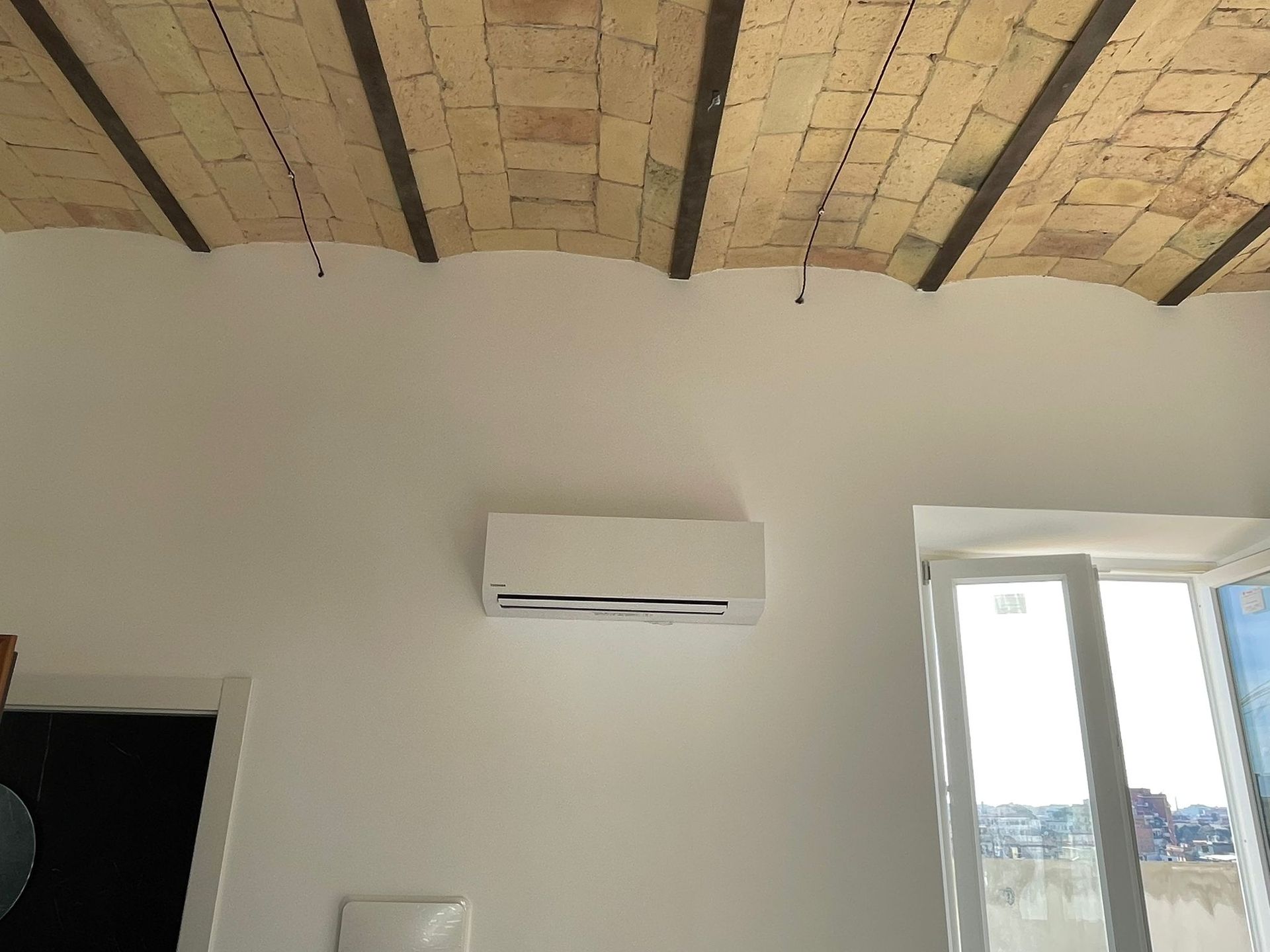 Una stanza con una parete bianca e un soffitto in legno.