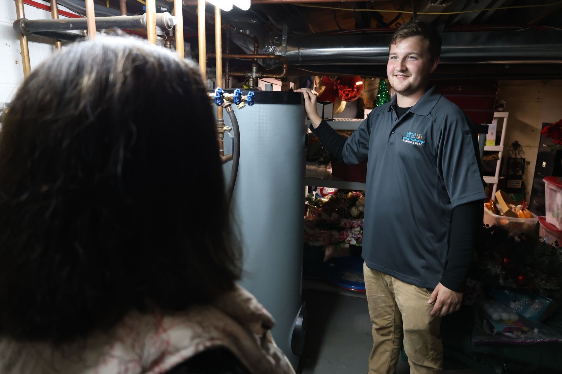 A man is standing next to a woman in a basement next to a water heater.