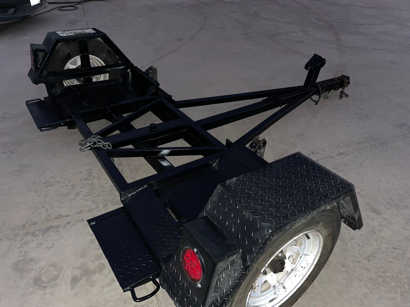 Un remolque negro está estacionado al costado de la carretera.