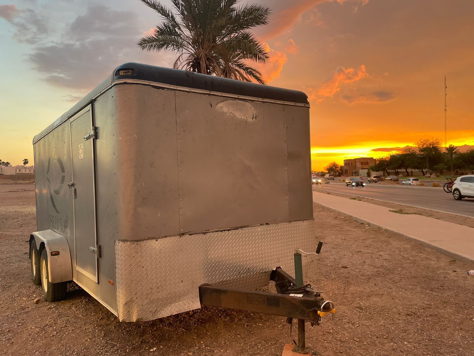 Un remolque está estacionado al costado de la carretera al atardecer.