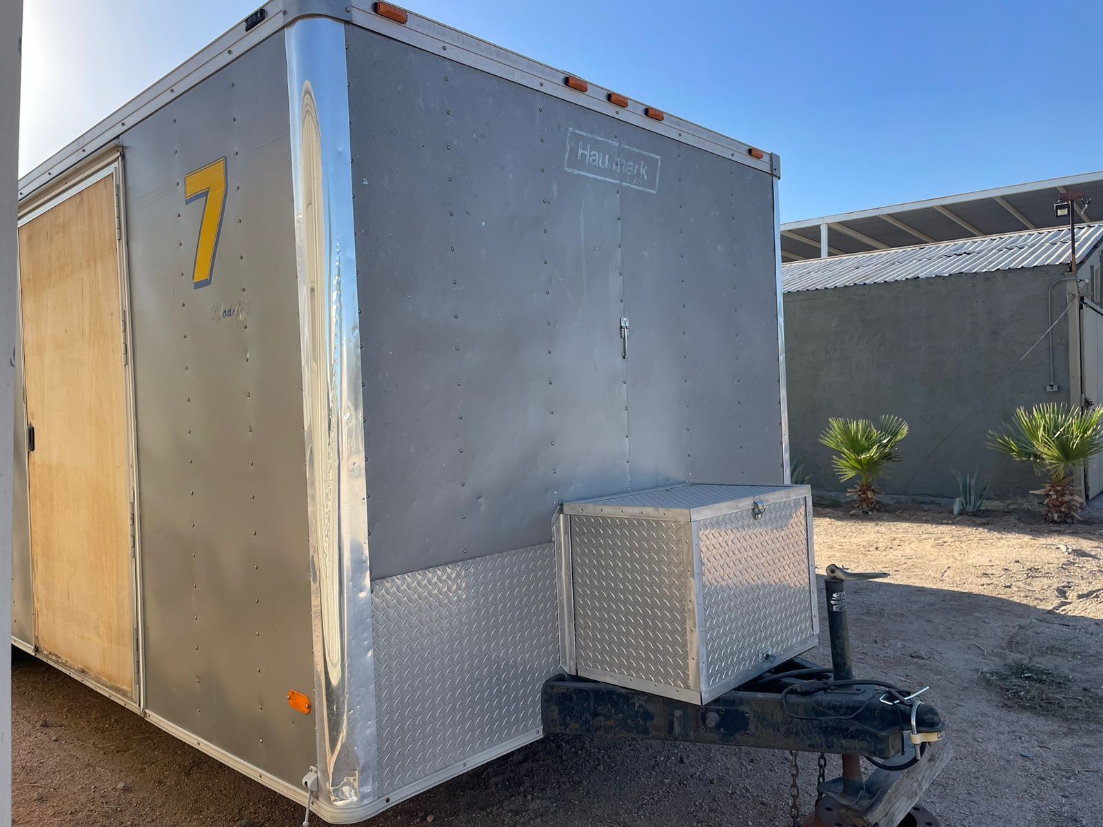 Un remolque con el número 7 está estacionado en un lote de tierra.