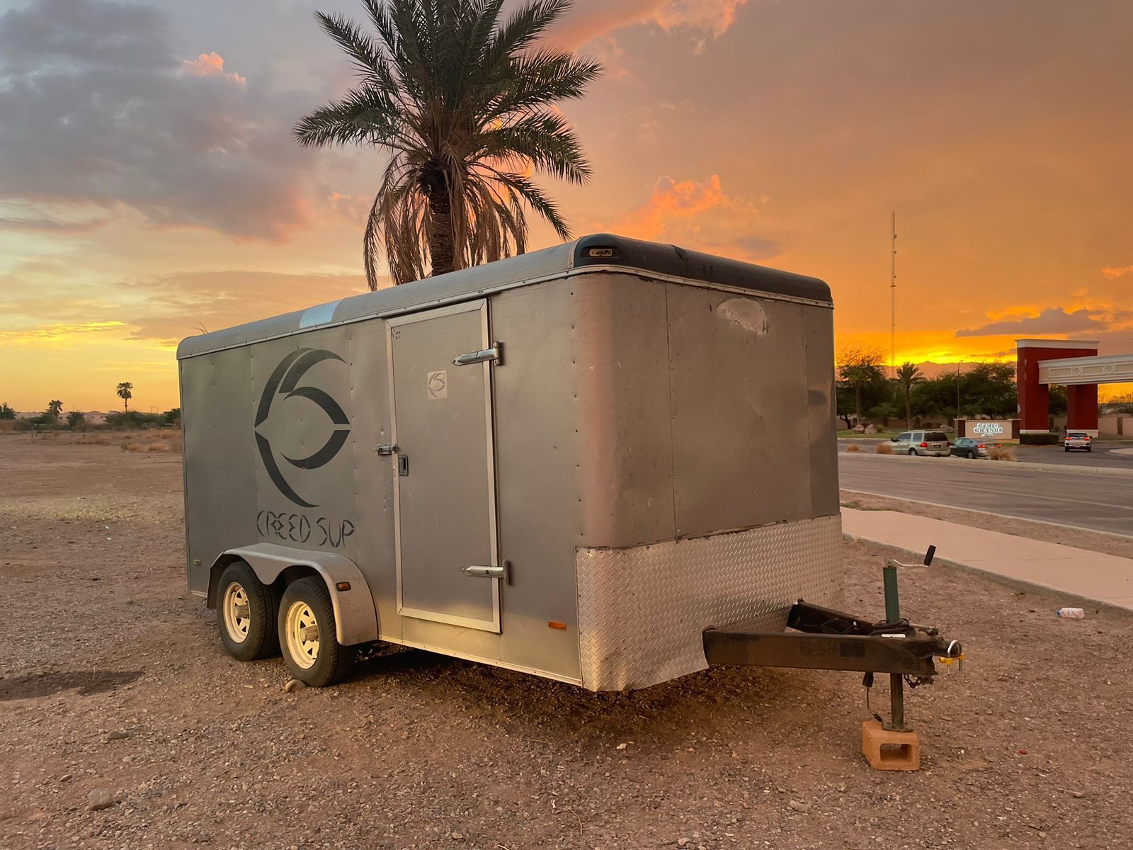 Un remolque está estacionado al costado de la carretera frente a una palmera.