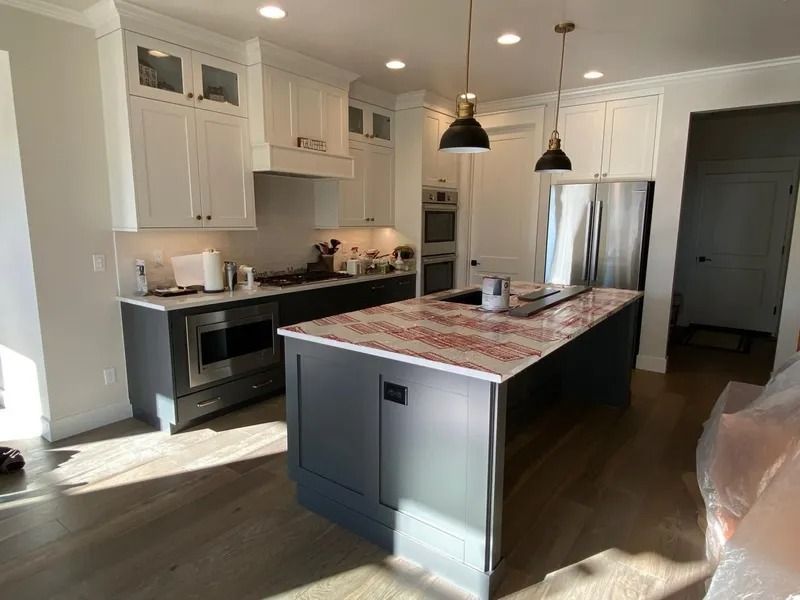 Modern kitchen with white cabinets, dark island, stainless steel appliances, and pendant lights