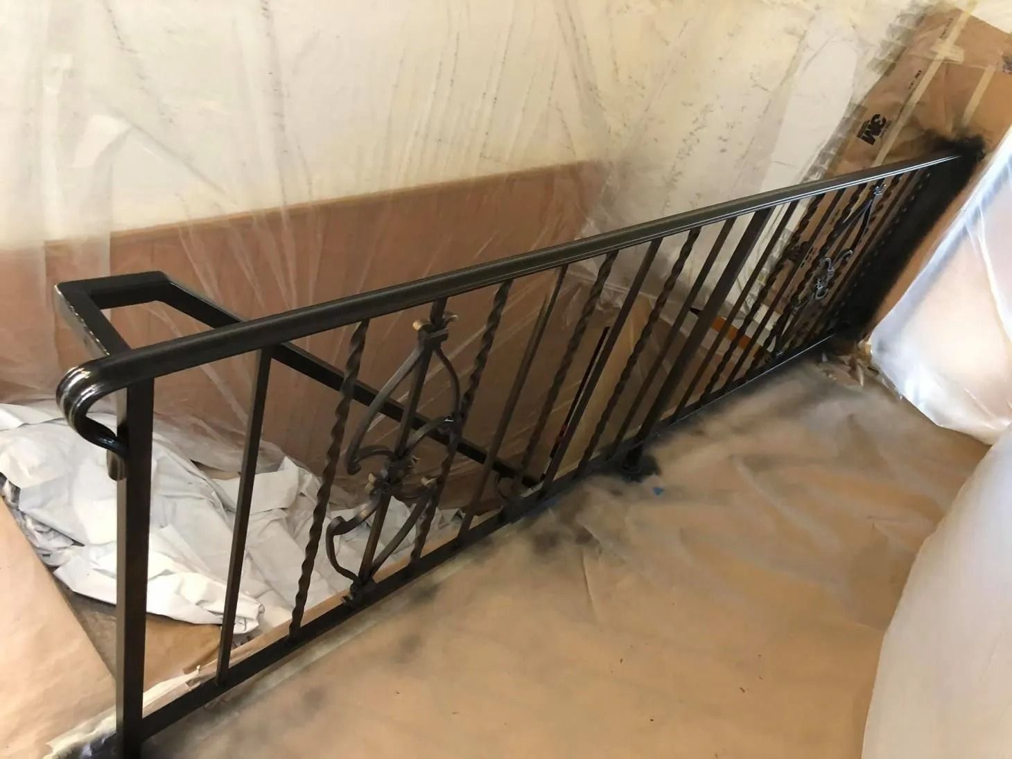 Black metal stair railing beside a carpeted staircase in an indoor hallway