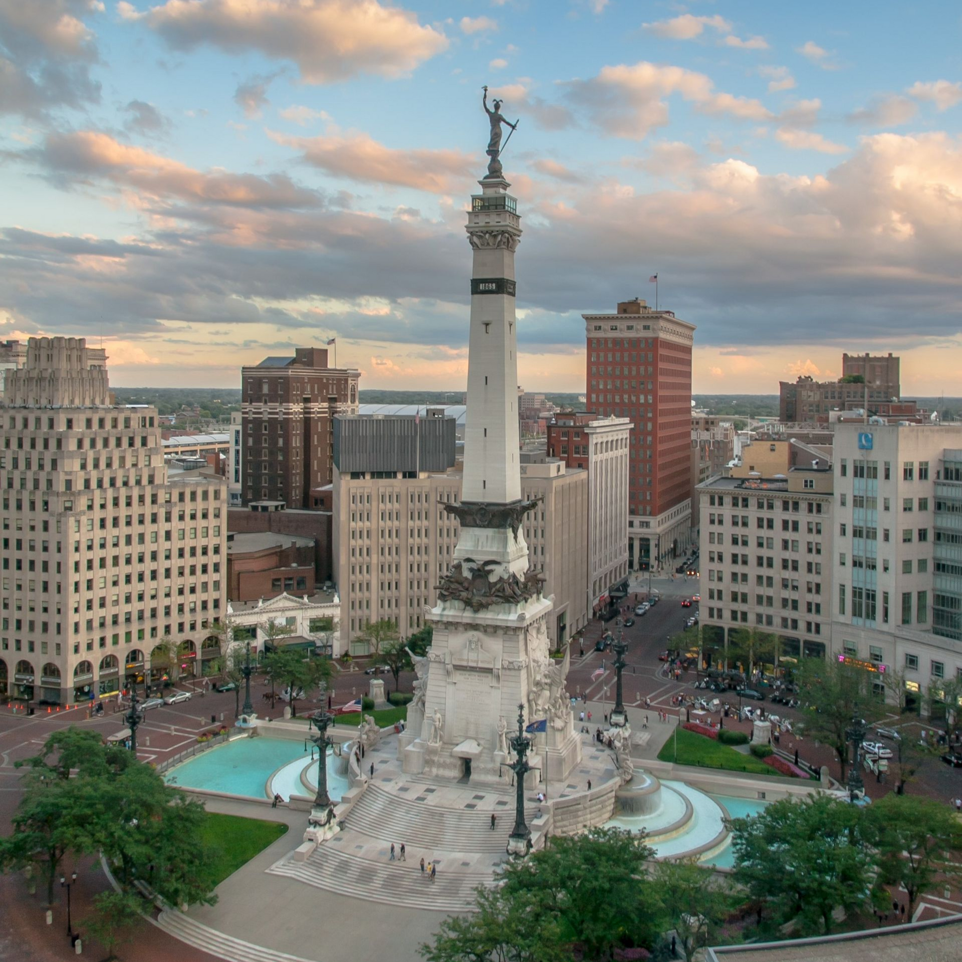 Monument Circle, Indianapolis. A tall, white monument in a plaza, surrounded by buildings and a cloudy sky.