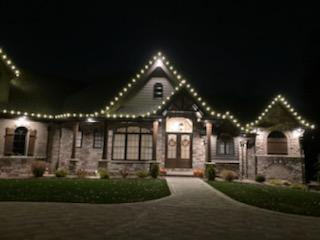 a large house with christmas lights on the roof is lit up at night — Louisville, OH — Mongiardo Power Wash