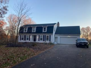 a white house with a black roof and a car parked in front of it — Louisville, OH — Mongiardo Power Wash
