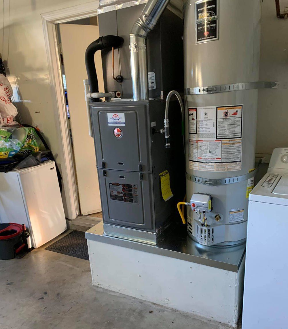 A gas heater and a water heater are sitting next to each other in a laundry room.